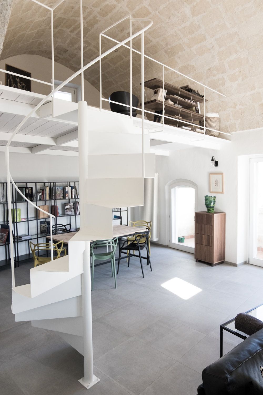 La filigrana scala a chiocciola in ferro piegato laccato bianco, realizzata su disegno. Il soppalco si inserisce dove inizia l’antica volta a botte in tufo. Per metterla in sicurezza sono stati riparati tutti i giunti fra le singole pietre.