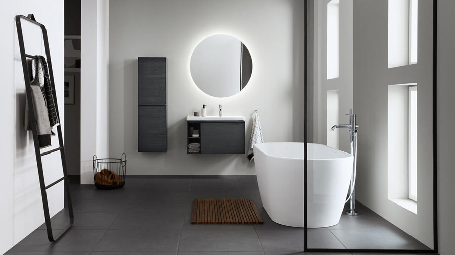 With an enveloping and discrete freestanding bathtub, a round and minimalist mirror and black brushstrokes which decorate the wall units and outline the towel rack...
